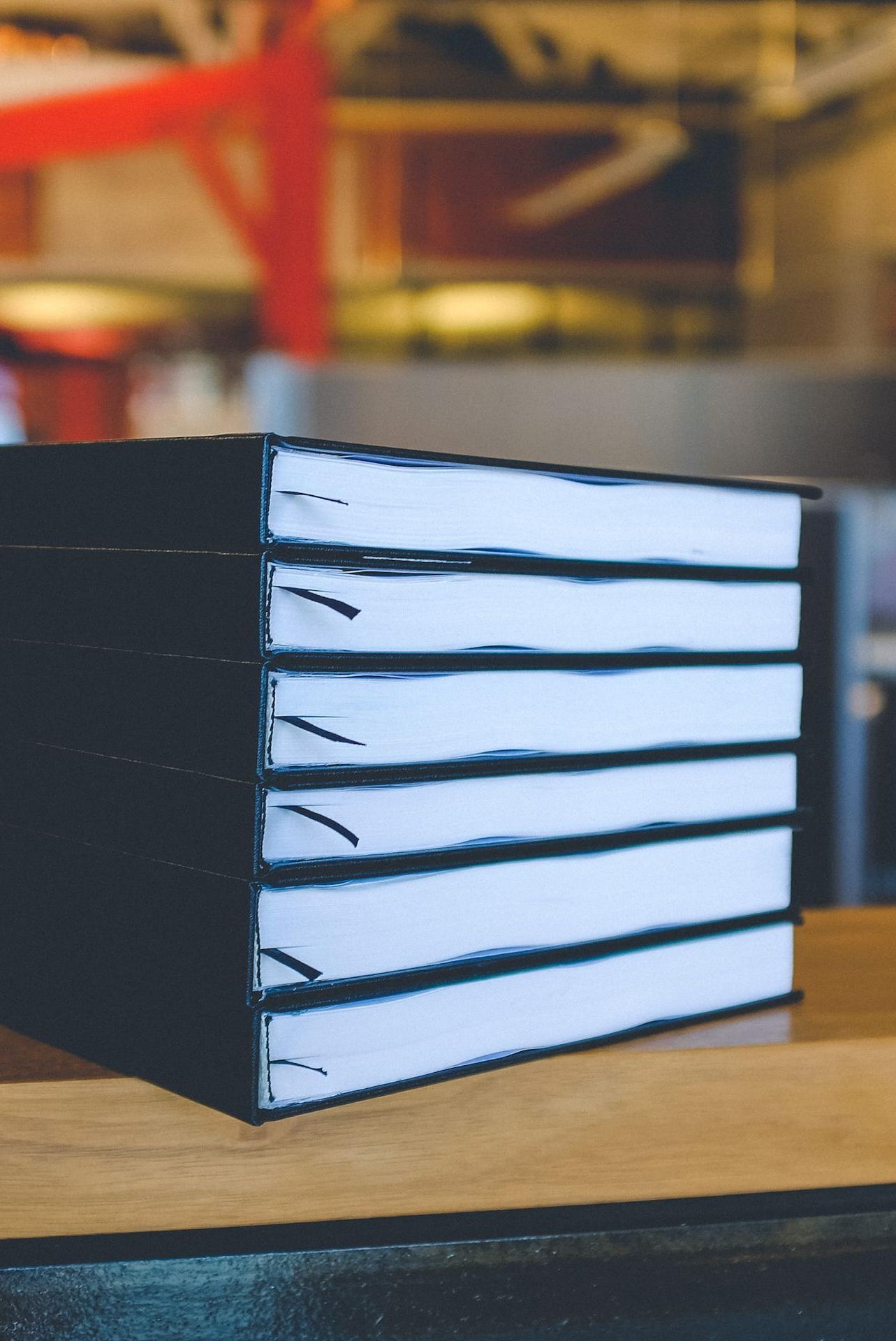 six black books on top of brown wooden table